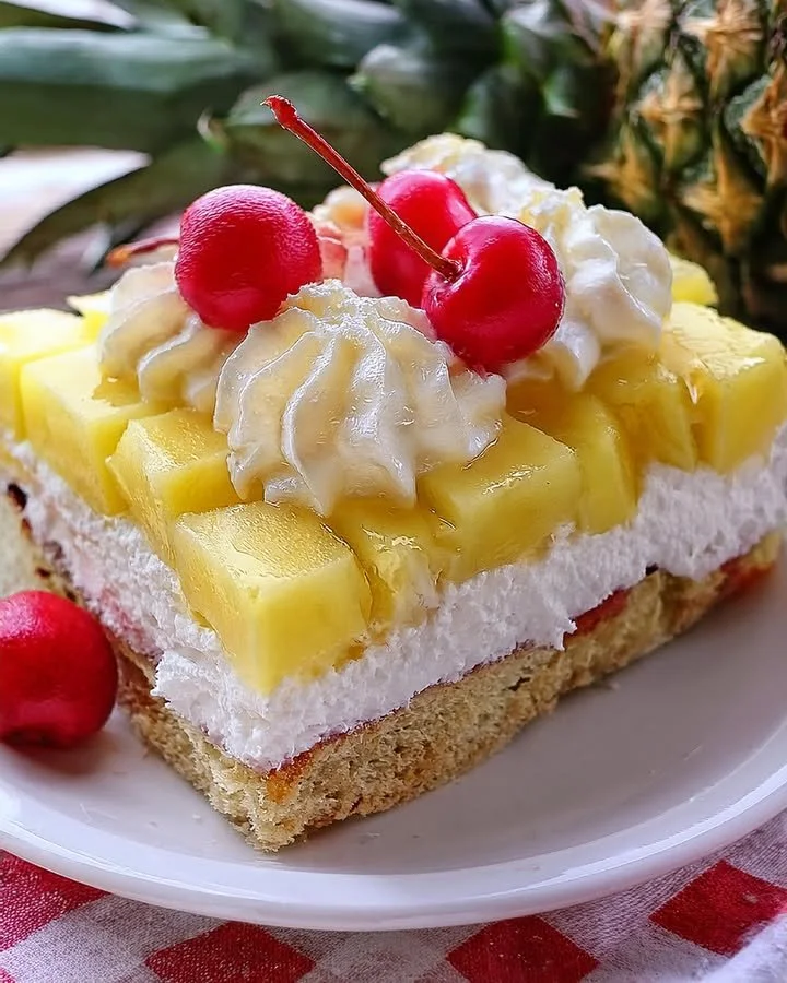 Delicious slice of Pineapple Heaven Cake topped with fresh pineapple and cream.