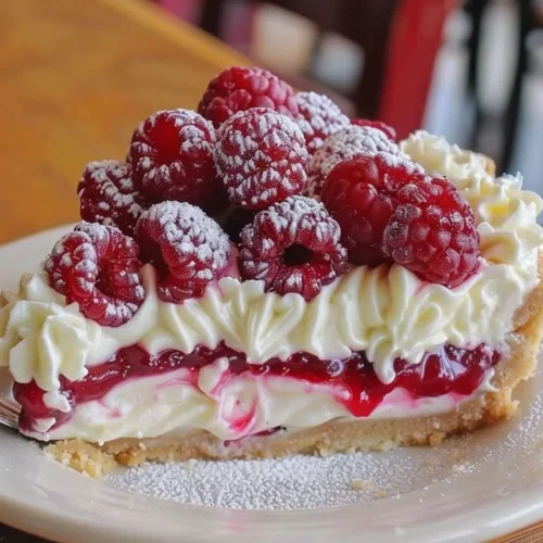 Delicious Raspberry Cheesecake Pie topped with fresh raspberries and creamy filling.