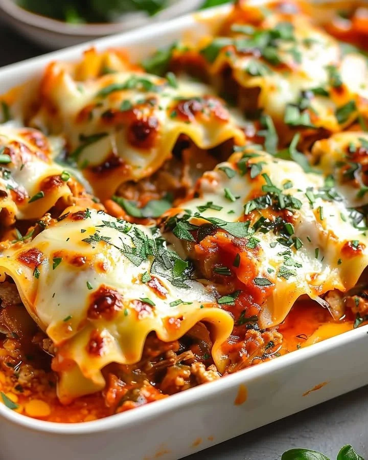 Delicious Short Rib Lasagna Rolls served on a plate with fresh herbs.